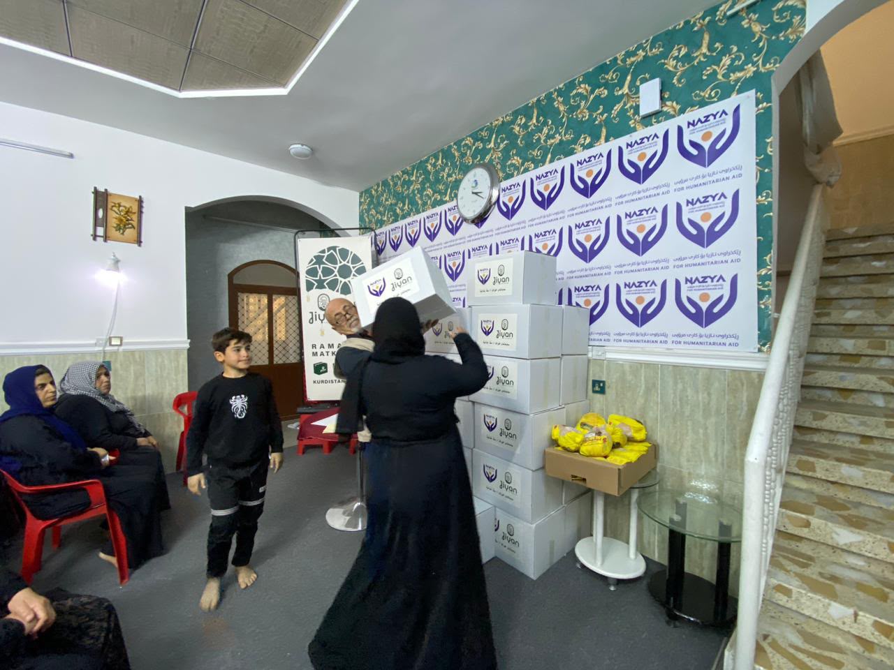 Nazya Organization distributing Ramadhan food baskets containing rice, oil, dates, and essential goods to families in Kurdistan